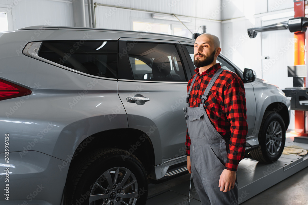 Male mechanic working at a repair shop and holding tools Male mechanic working at a repair shop and holding tools