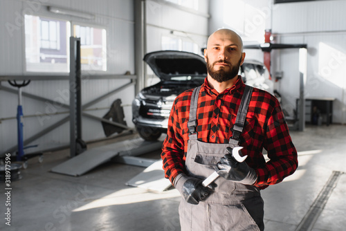 Mechanic working and holding wrench of service order for maintaining car at the repair shop