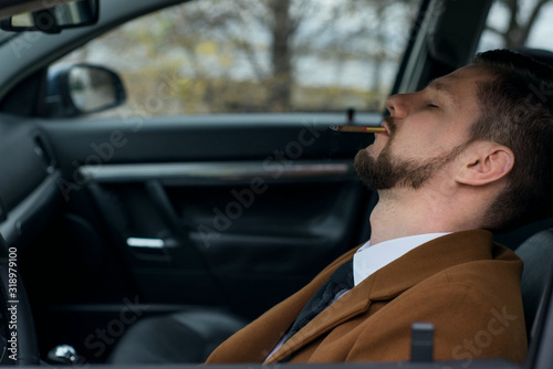 Portrait of a young drunk guy sleeping with a cigarette while driving a car. Close-up. In a warm, creative tone © Алексей Доненко