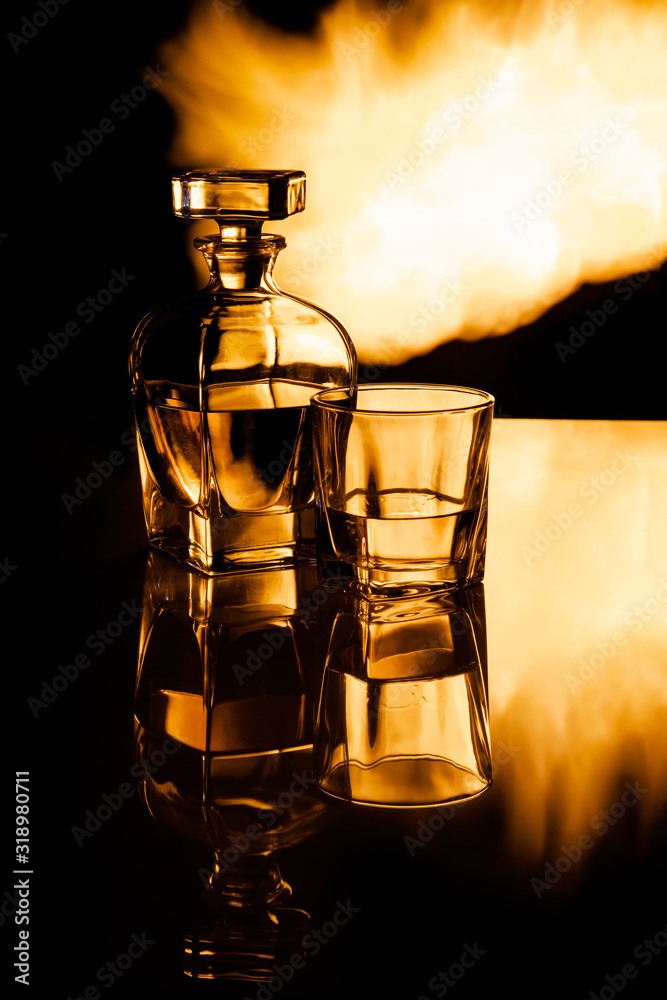 Karafka z whisky oraz szklanka na tle płomieni ognia, efekt odbicia