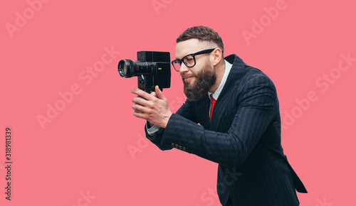 Filmmaker with a vintage lomo camera. Professional Videography. Man with beard in trendy formal suit. Studio