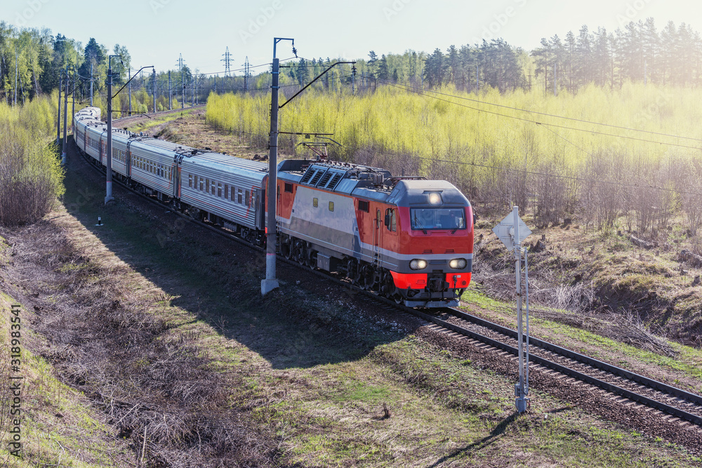 Naklejka premium W wiosenny poranek do stacji zbliża się pociąg pasażerski.