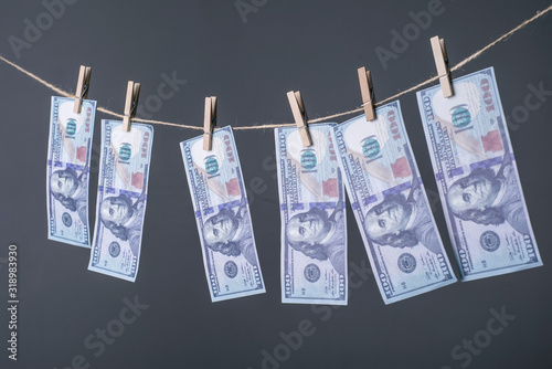 Close-up of money, dried on the ropes, fastened with clothespins. The concept of drying money. On a gray background Money Laundering concept. US dollars hung out to dry and clean