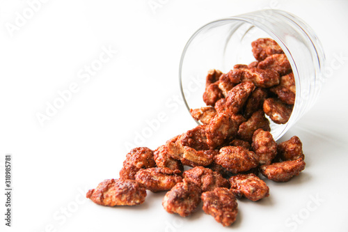 Obraz na plátne Sugar roasted pecan nuts (caramelized, praline nuts) in a glass on a white backg