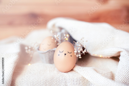 Delicate composition of flowers and eggs with a painted cute face.