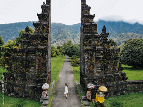 Tourist woman walking through Traditional Balinese Hindu gate Candi Bentar close to Bedugul, Bratan lake Bali island Indonesia. Vacation on Bali Drone photo photo