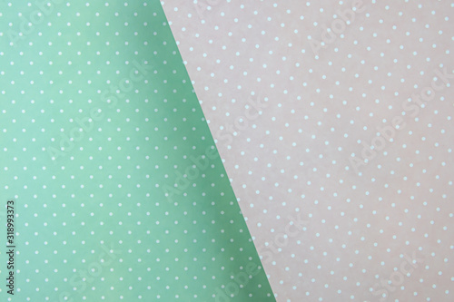Colored paper background. delicate pastel color, mint green and pink in white polka dots. diagonally, with a shadow