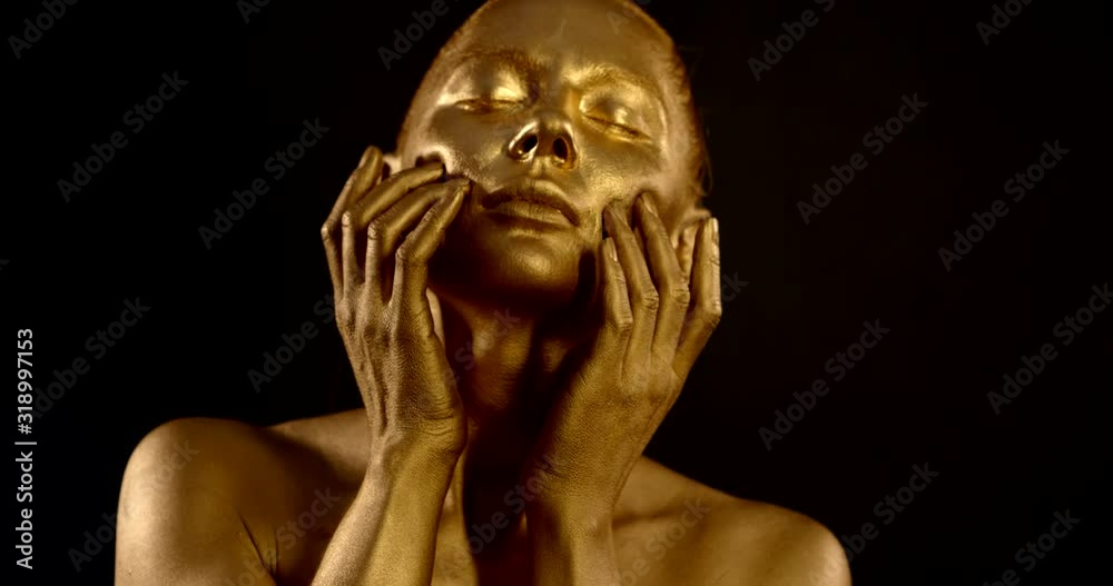 Close-up portrait of a gentle naked girl, she is in the Studio on a black background, she has a Golden pigment on her skin. she poses, makes movements with her hands on her face. Close-up portrait of a gentle naked girl, she is in the Studio on a black background, she has a Golden pigment on her skin. she poses, makes movements with her hands on her face.