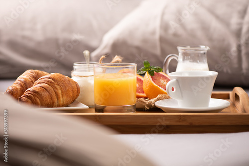 Continental breakfast. Breakfast tray on bed with coffee, orange juice and croissant
