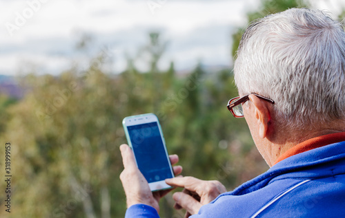 Rear view of old man taking a photo with his mobile phone