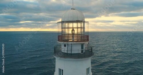 Picturesque white lighthouse at the sunset. 4k footage. Aerial view.