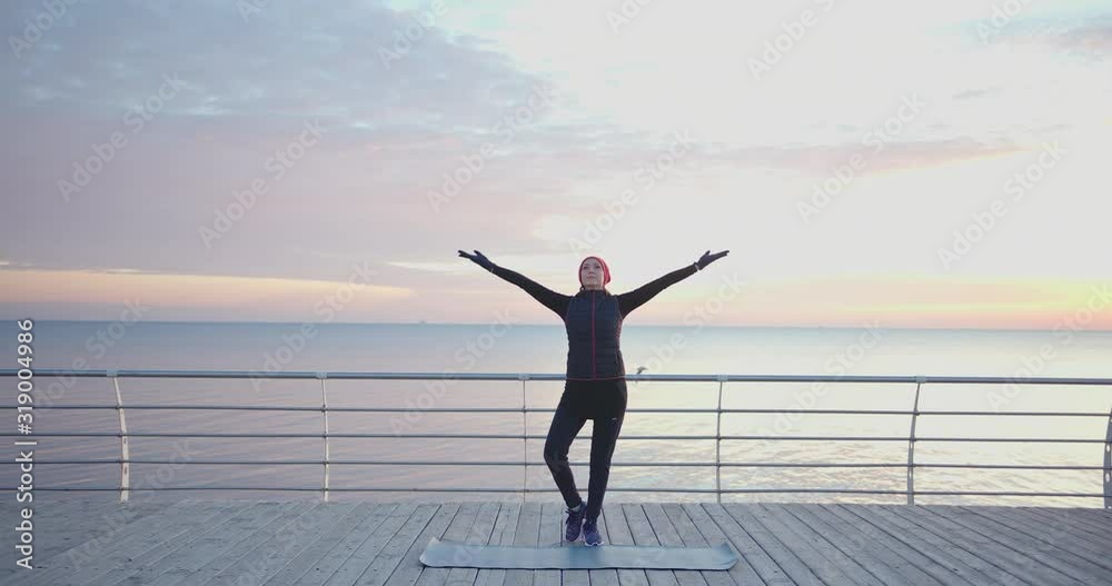 Young brunette woman doing yoga exercises on wooden sea embankment in the morning. healthy lifestyle and meditation. Young brunette woman doing yoga exercises on wooden sea embankment in the morning. healthy lifestyle and meditation.