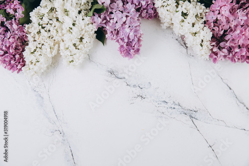 Floral pattern of a branch of lilac on a trendy marble background. Top view. Flat lay. Spring concept. Copy space
