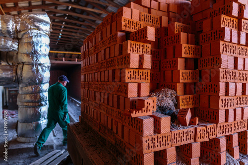 Production of clay bricks at a brick factory. Ready hot red bricks stacked on pallets cools after kiln firing.
