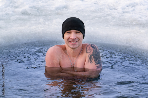 The man in the hat froze in ice water and shakes from the cold. Winter swimming