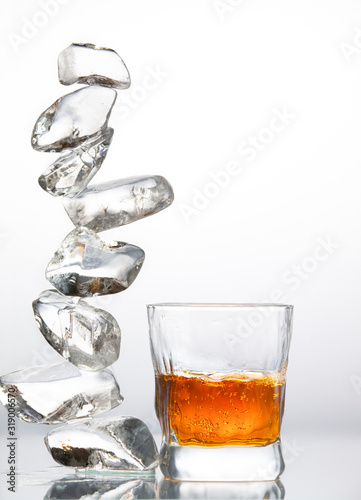 Cuadro en lienzo A low transparent glass with alcohol and pieces of ice folded in a column