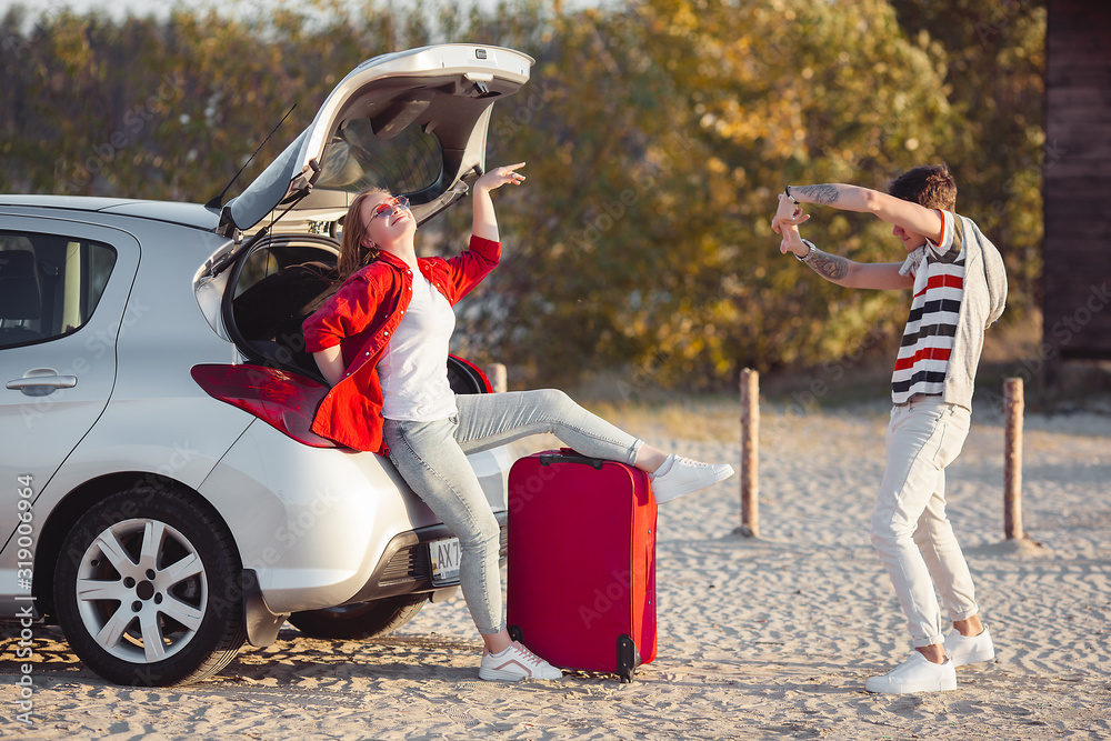 Obraz premium Young couple traveling on the car. Woman and man having a trip on automobile. Happy young people outdoors.