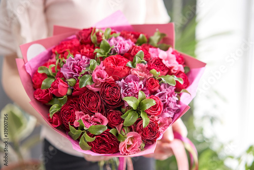 European floral shop. Beautiful bouquet of mixed flowers in womans hands. the work of the florist at a flower shop. Delivery fresh cut flower.