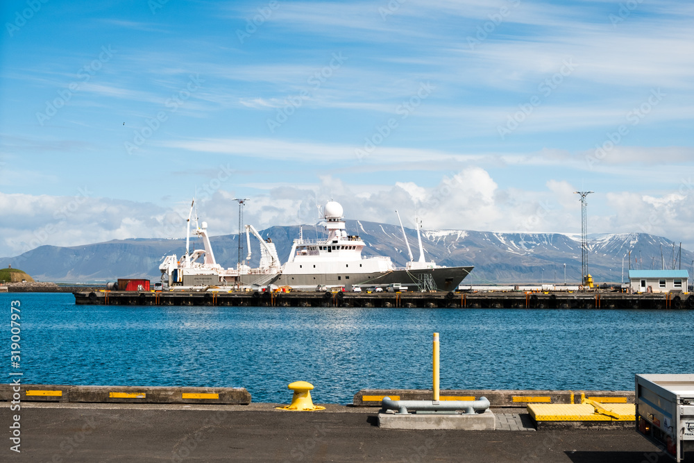A large white ship in one of the harbors at Reykjavik, Iceland with a view of a mountain range in the distance