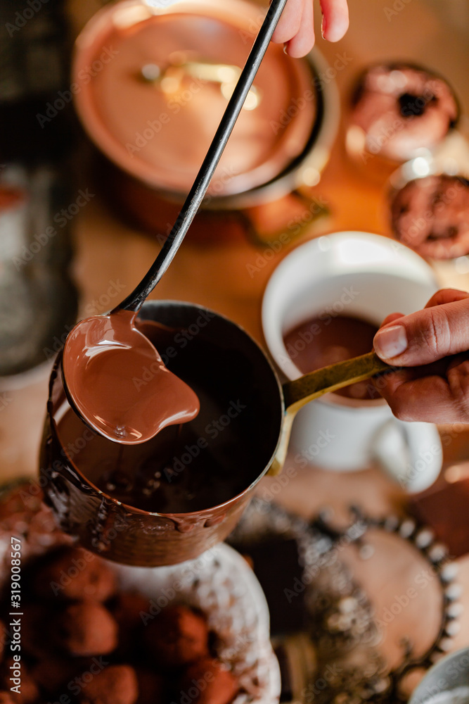Fototapeta premium Process of preparation of delicious organic hot chocolate in old vintage ladle. Soft daylight, lifestyle photography, process of tasty drink creation. Close up, macro