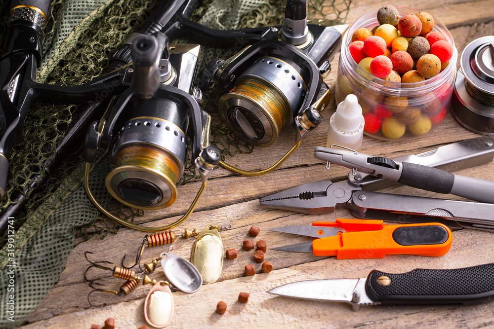 Fishing rods and spinnings in the composition with accessories for fishing on the old background on the table