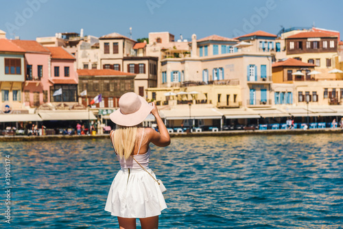 Attractive female tourist/ influencer taking photo with a smartphone during sumer vacation. Chania, Crete, Greece
