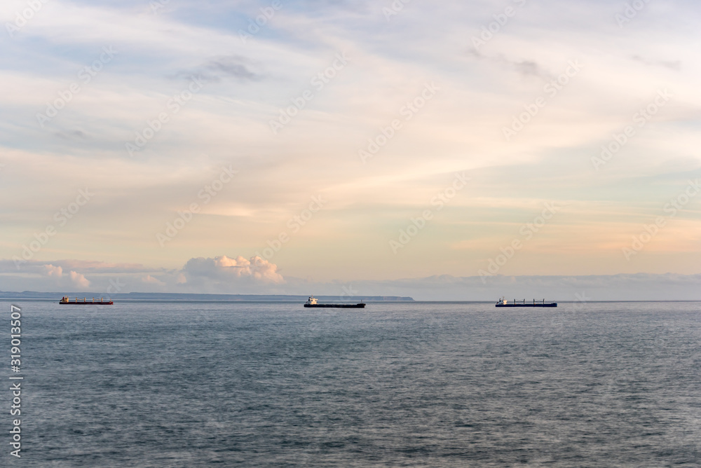 Freight ships anchored on calm sea outside Lisbon in afternoon