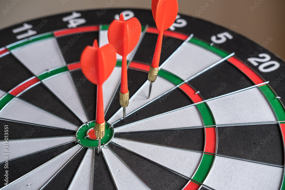 Red and yellow dart arrows hitting in the target center of dartboard. Success hitting target aim goal achievement concept Red and yellow dart arrows hitting in the target center of dartboard. Success hitting target aim goal achievement concept