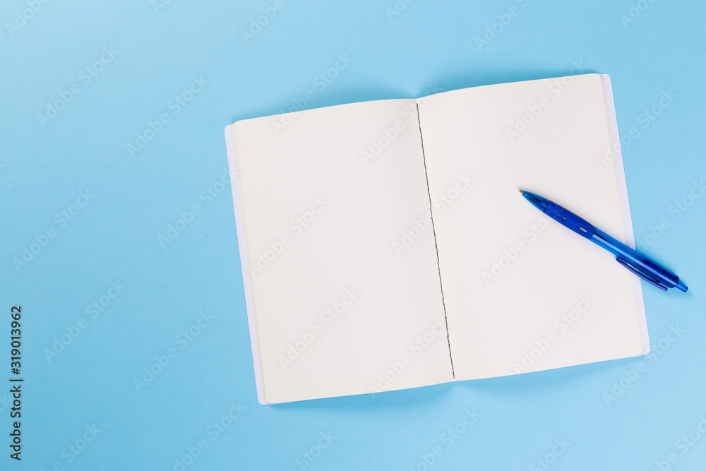 top view of empty open notebook on blue background, office equipment, school supplies and education concept top view of empty open notebook on blue background, office equipment, school supplies and education concept