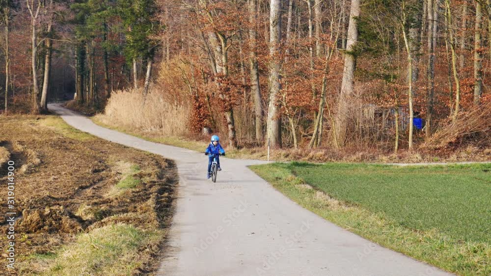 Kleiner Junge fährt mit Helm Fahrrad auf einer Landstrasse Kleiner Junge fährt mit Helm Fahrrad auf einer Landstrasse