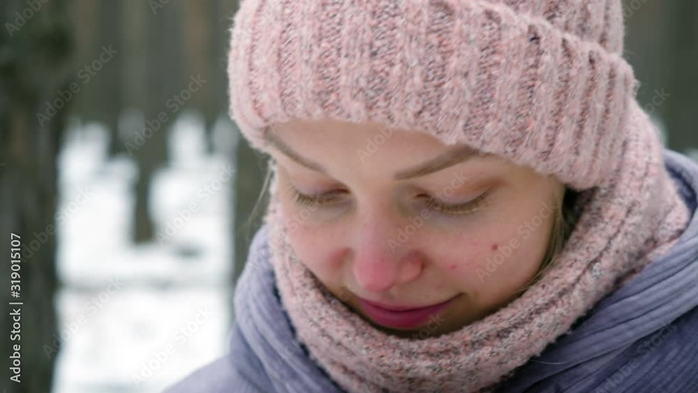 Close-up shot of young smiling beautiful girl in winter clothes holding in her hands cup of hot tea in pine forest. 4K Close-up shot of young smiling beautiful girl in winter clothes holding in her hands cup of hot tea in pine forest. 4K