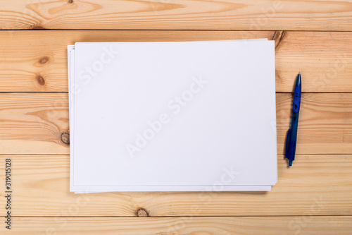 A4 white paper with pen on wooden background. Blank branding template. Photo blank form. Layout for portfolio design.