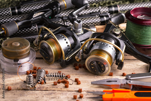 Fishing rods and spinnings in the composition with accessories for fishing on the old background on the table