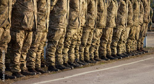 Soldiers legs in military uniform and boots standing in line at camp