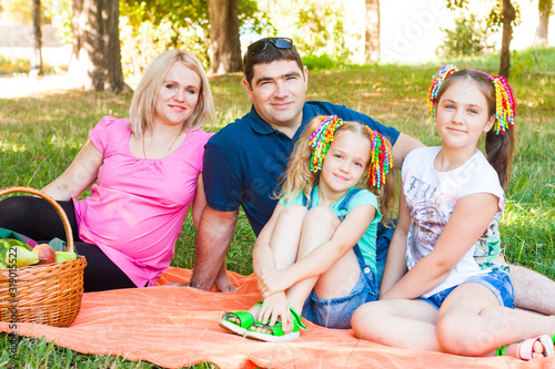 Obraz na płótnie Happy Two Parent Family With Two Daughters On Orange Picnic Blanket In The Park w salonie