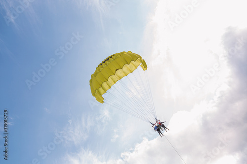 Beach extreme adventures during summer holidays concept. Couple of man and woman flying with yellow parachute over sea water pulled by motorboat. Horizontal color photography.