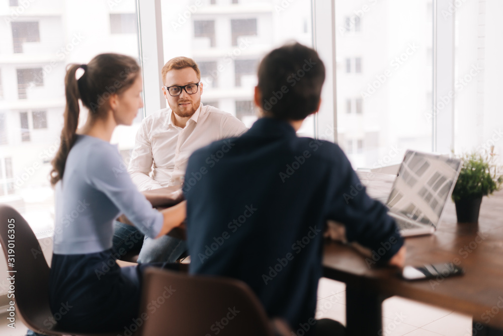 Confident young businessman presenting project to client, making business offer, convincing customer to close deal in modern office meeting. Concept of office life.