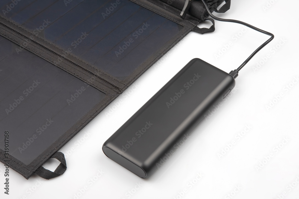 The solar panel charges the power bank battery for the smartphone on a white background. digital technologies and devices The solar panel charges the power bank battery for the smartphone on a white background. digital technologies and devices