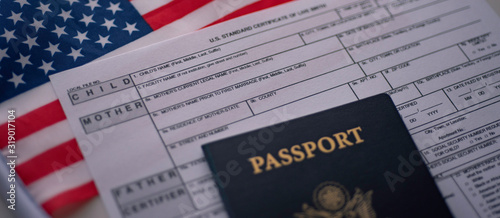 U.S. standard certificate of live birth application form next to American flag and Passport of USA. Wide photo. Birthright citizenship concept. photo