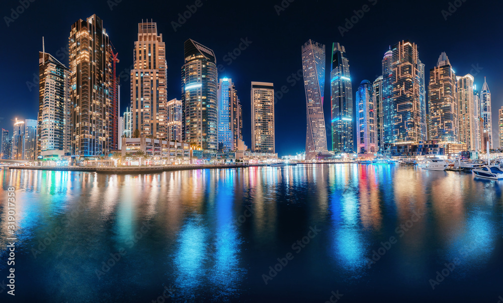 Obraz premium Night colorful view of the famous tourist attraction of the city of Dubai - Marina seaport and illuminated skyscrapers. Travel and real estate in United Arab Emirates