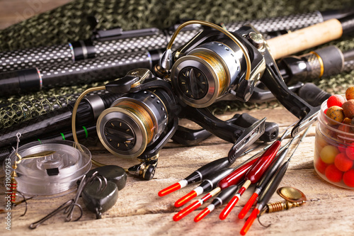 Fishing rods and spinnings in the composition with accessories for fishing on the old background on the table