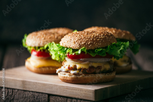 Fresh tasty grilled beef burgers with cheese wood background.