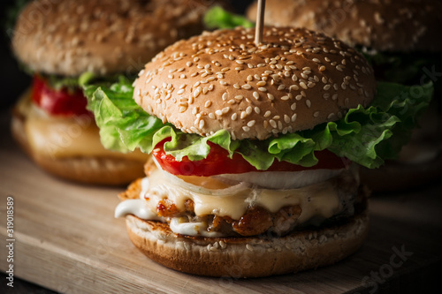 Fresh tasty grilled beef burgers with cheese wood background.