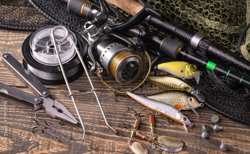 Fishing rods and spinnings in the composition with accessories for fishing on the old background on the table