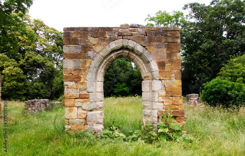Canvas Print Ruined stone archway in grassy field
