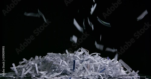 Side view of pile of shredded paper against black slow motion