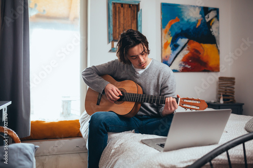 young man playing guitar in his room