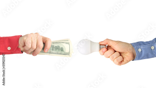 two hands with dollar bills and an led lamp on a white background. Payment for electricity. Buy led lamp. Business industry