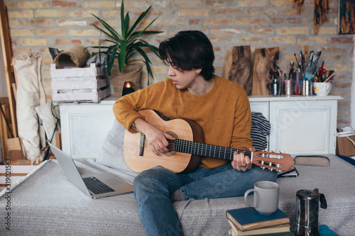 young man playing guitar in his home