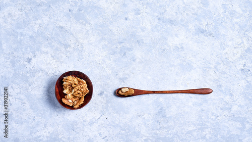 walnut in a wooden bowl with a wooden spoon on a blue background, top view